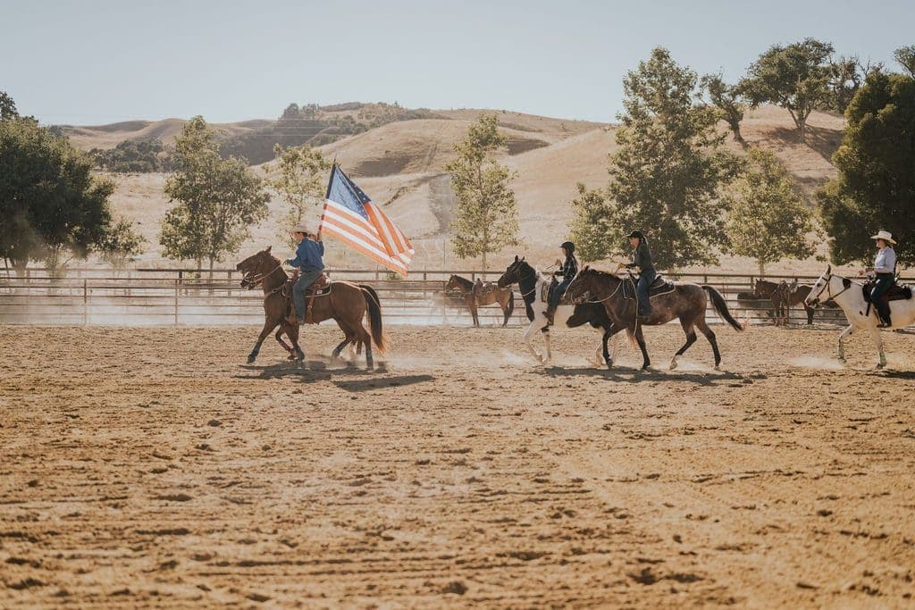 group of people riding horses and on person riding and holding an American flag