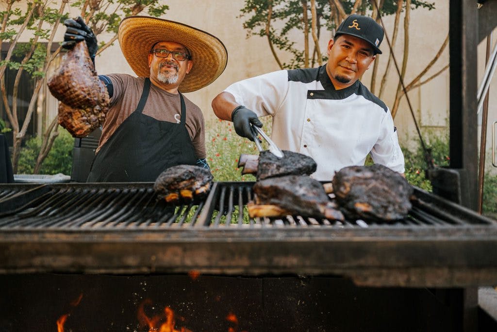 two cooks barbecuing meat at Grand BBQ