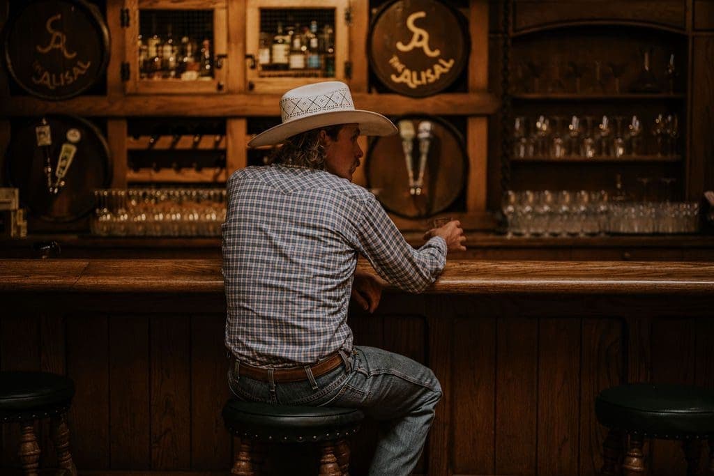 person in cowboy hat sitting at a bar