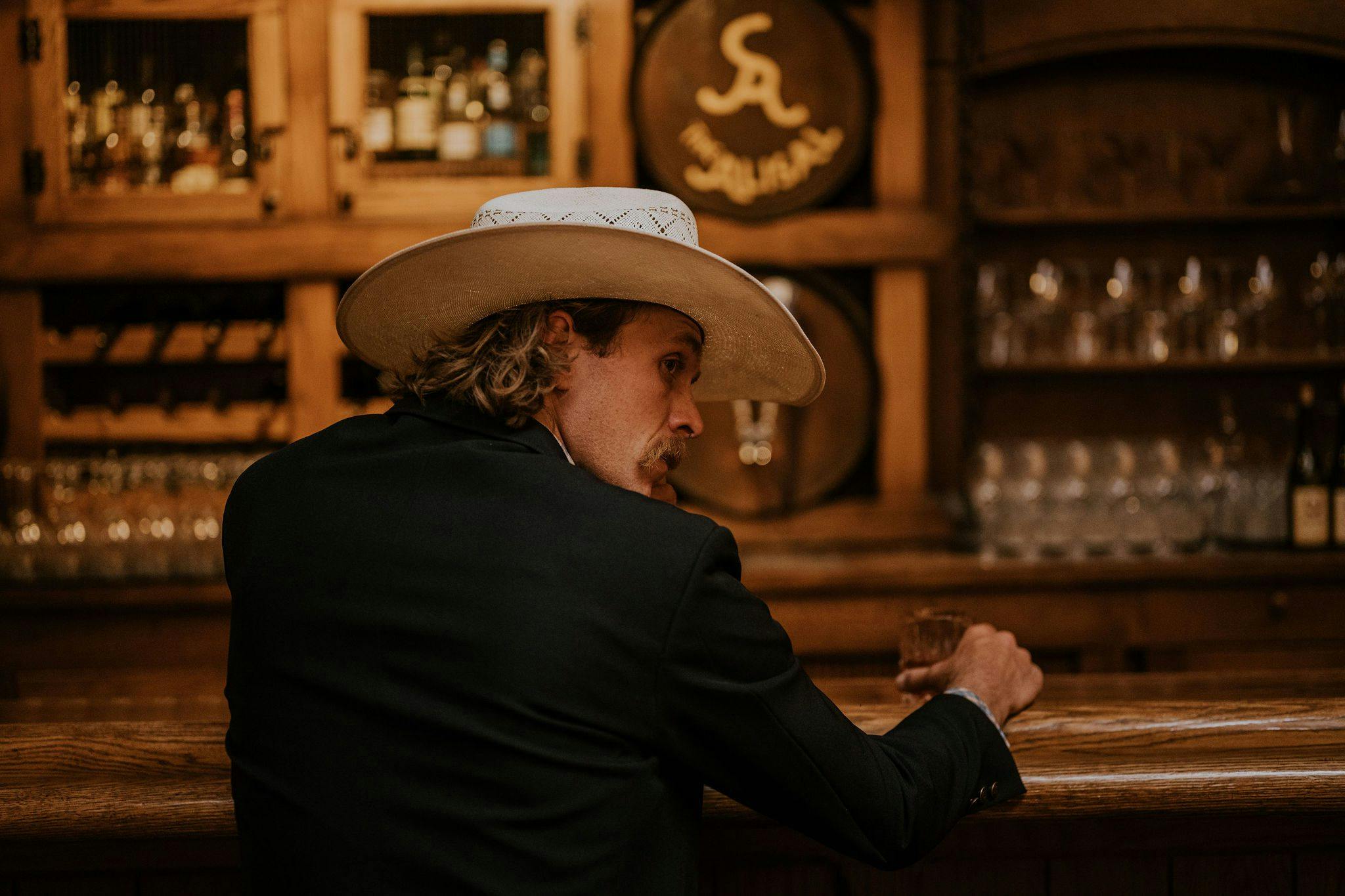 person wearing cowboy hat sitting at a bar