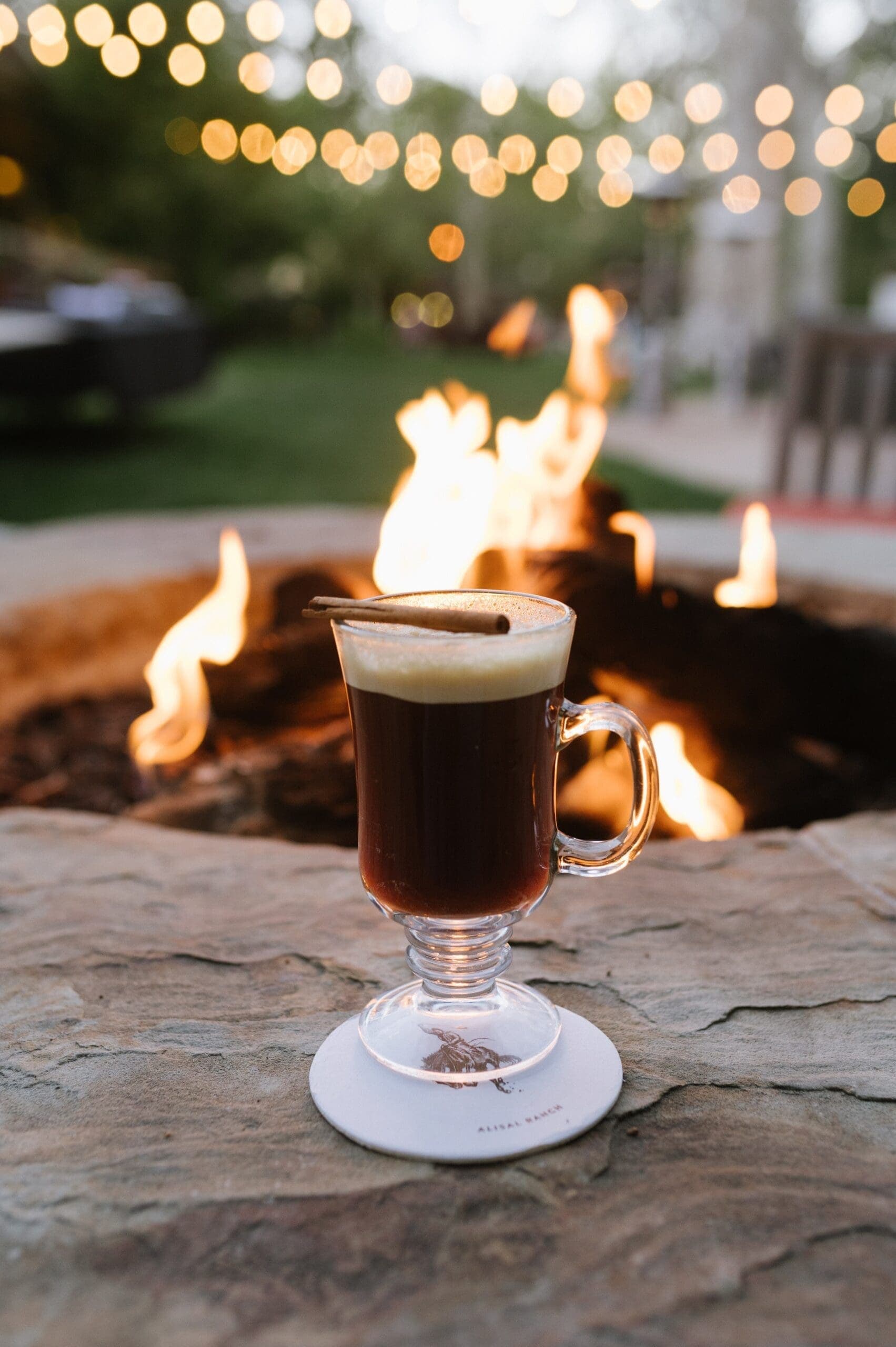 drink in a glass by a fire pit