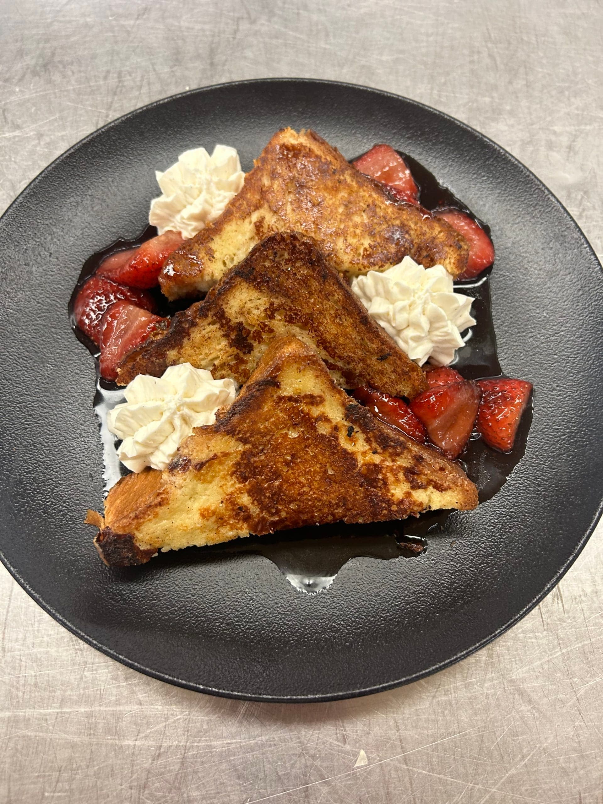 french toast with strawberries and whipped cream on a plate