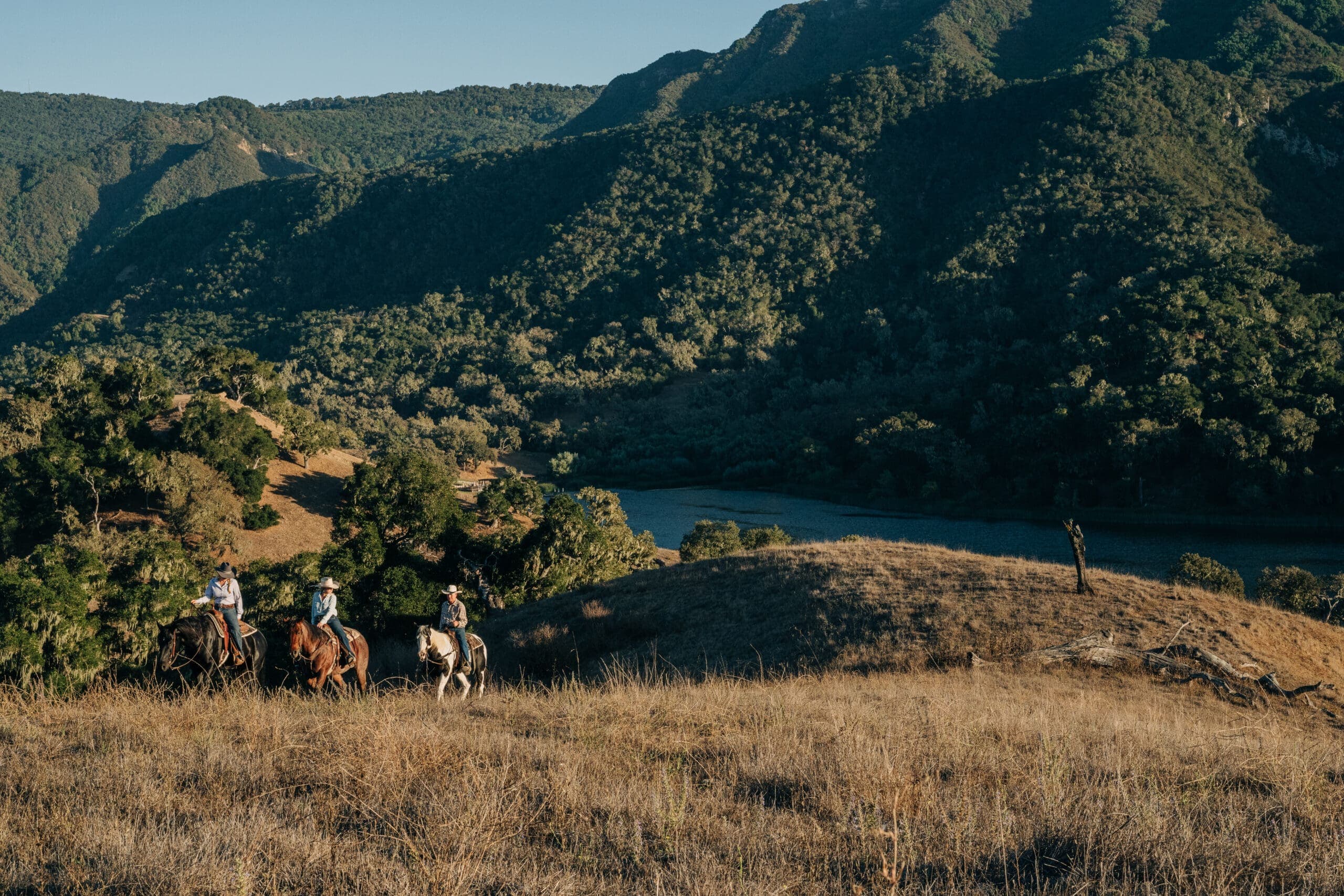 Wranglers riding horses overlooking Alisal Lake